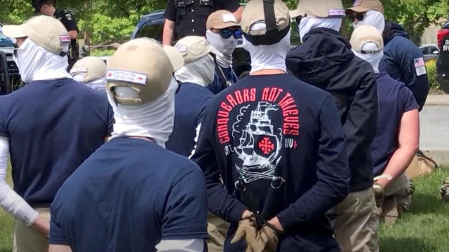 Police officers in riot gear guard a group of men who police say are among 31 arrested for conspiracy to riot and appear to be affiliated with the group Patriot Front in Coeur d'Alene, Idaho, June 11, 2022, in this still image obtained from a social media video. 