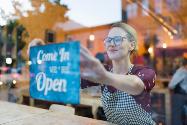 Business owner setting up open sign in cafe window 