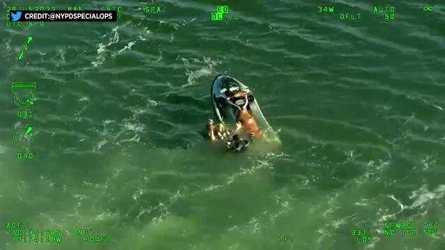An NYPD diver helps a man floating in the water in Jamaica Bay near a Jet Ski 