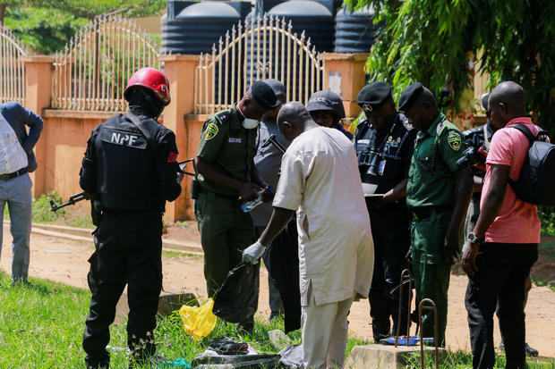 Security officers inspect items suspected to be explosives outside the medium-security prison in Kuje 