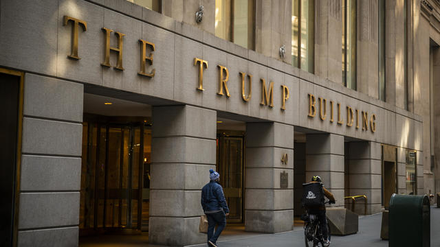 A building in Manhattan with the words "The Trump Building" on the side in large gold letters 
