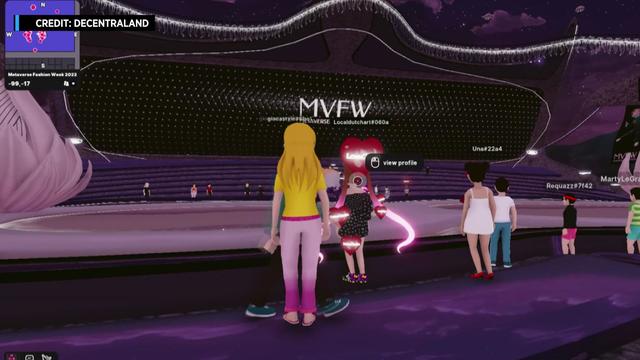 A screenshot from the Metaverse platform Decentraland showing multiple avatars standing in a large room. 