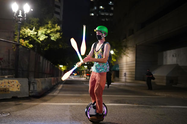 Masked protester on unicycle at night 