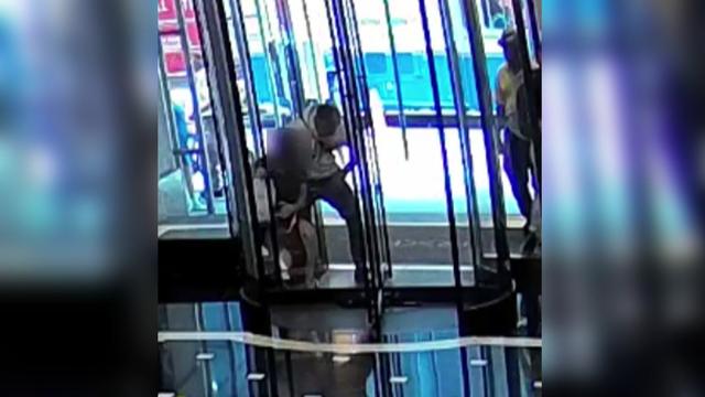 Surveillance video shows a man and a woman struggling over a French bulldog inside a revolving glass door. 