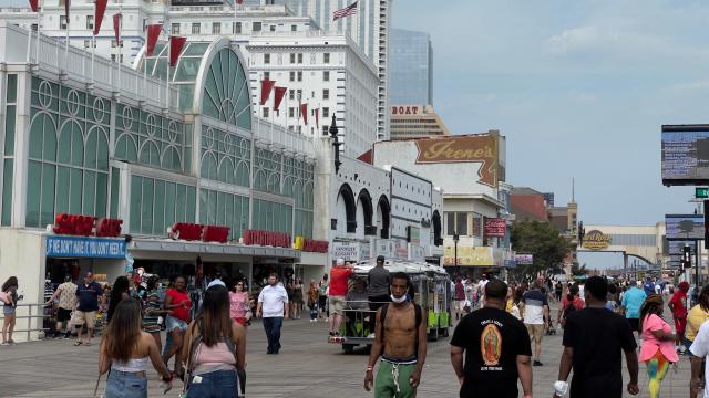 People walk on the boardwalk in Atlantic City, New Jersey, past the Hard Rock Hotel. 