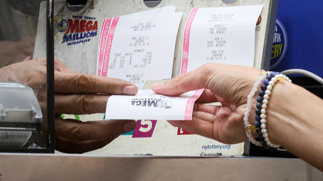A woman buys a ticket for the Mega Millions lottery drawing at a newsstand in New York City, July 26, 2022. 