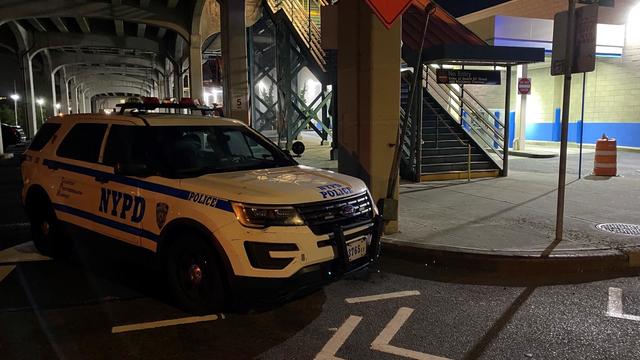 An NYPD vehicle sits next to the entrance to a subway station. 