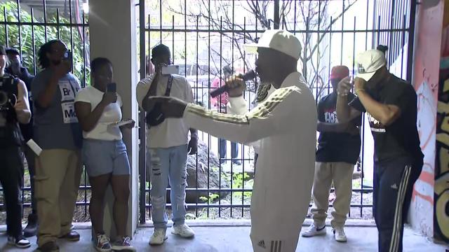 A man with a microphone performs in front of a crowd at a community center. 