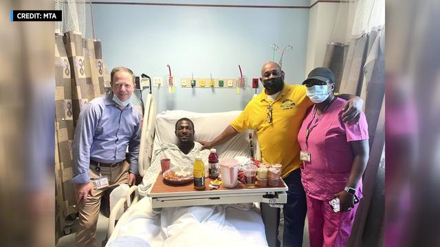 NYC Transit President Richard Davey stands next to MTA worker Anthony Nelson, who is laying in a hospital bed. 