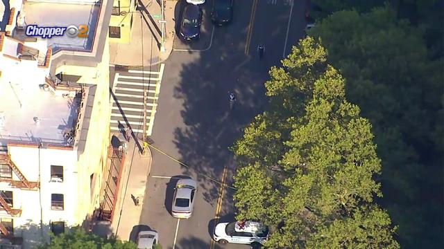 An aerial shot of crime scene tape blocking off part of a street in the Bronx. An NYPD vehicle and a few police officials can be seen. 