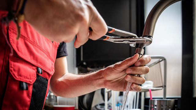 Repairman using adjustable pliers to fix kitchen faucet 
