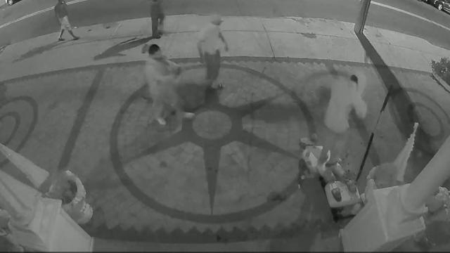Surveillance video shows someone jumping on a statue of Mahatma Gandhi that has been knocked to the ground. Nearby, someone holds a sledgehammer. 
