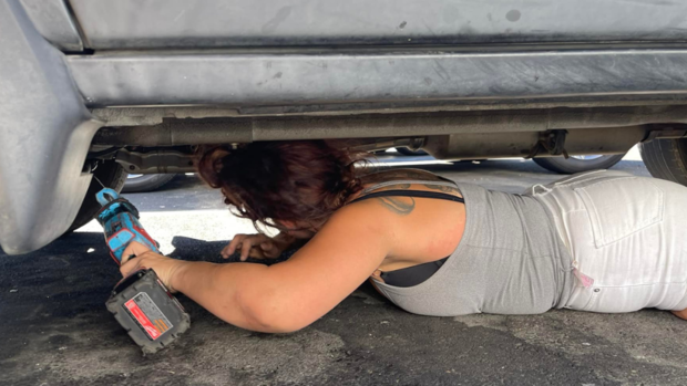 lady-under-vehicle-with-saw.png 