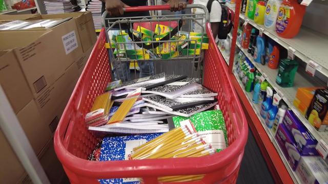 A shopping cart full of school supplies, including pencils, notebooks and crayons 