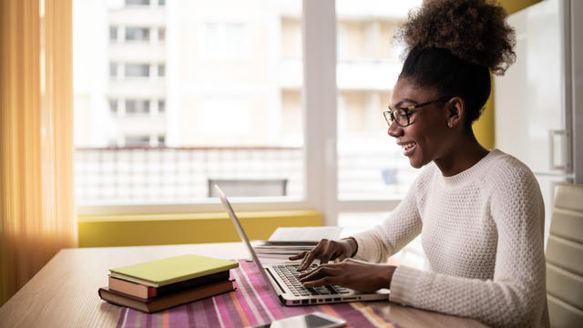 Afro Woman sitting at home using laptop and studying 