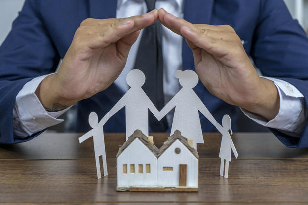 Insurer protecting a family with his hands; multiple exposure 
