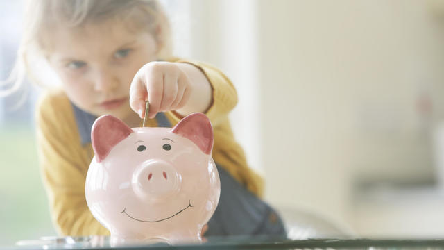 Young child putting coins into piggy bank 