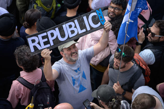 A anti-royalist protester holding a sign saying "Republic" 