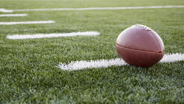 Close up of American football ball on green playing field 
