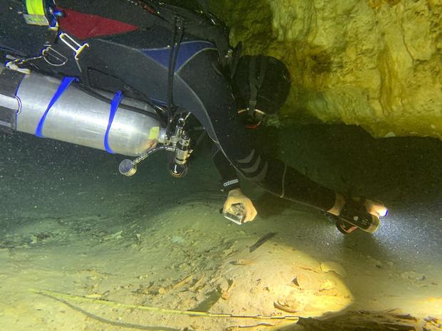 Aquatic archaeologist Octavio del Rio films a prehistoric human skeleton partly covered by sediment in an underwater cave in Tulum, Mexico 