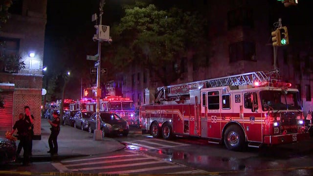 Several firetrucks sit parked on a street at night. 