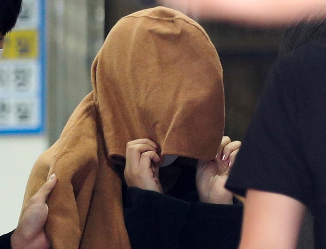A woman believed to be the mother of two children whose remains were found in suitcases in New Zealand last month is transported to prosecutors' office, in Ulsan