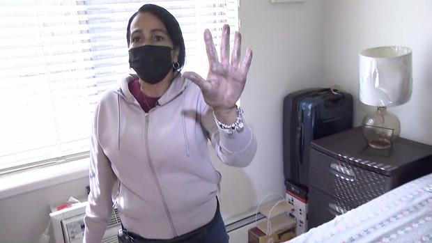 A woman holds up her soot-covered hand after rubbing her palm on her bed. 
