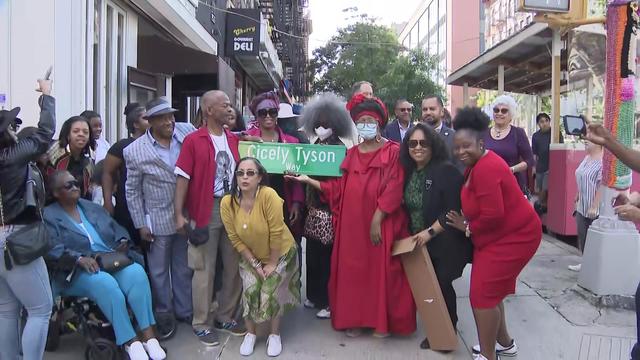 Relatives and others pose with a street sign reading, "Cicely Tyson Way." 