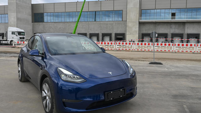 Blue Tesla Model Y in front of factory 