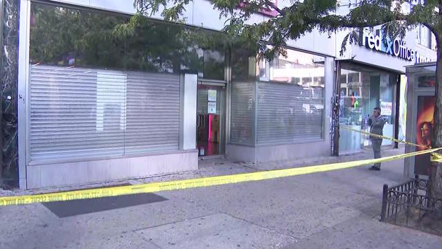 Crime scene tape blocks off a portion of sidewalk outside a cellphone store in Harlem. 