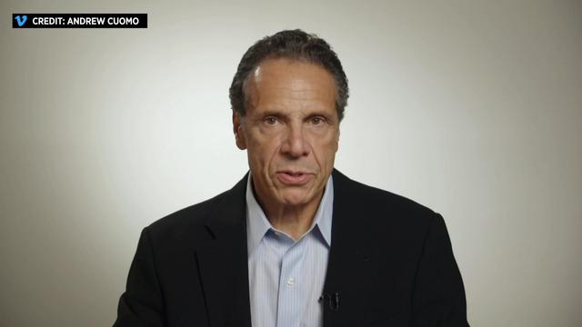 Andrew Cuomo sits in front of a white background. 