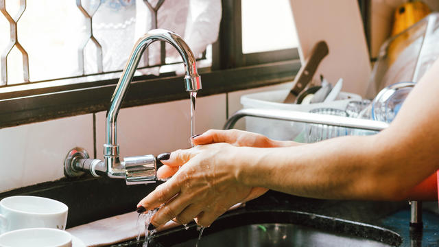 A woman washes her hands on a faucet 