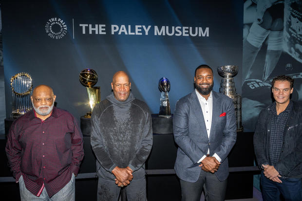Cecil Fielder, Ron Harper, Chris Canty, and Tukka Rask stand in front of he MLB's Commissioner's Trophy, NBA's Larry O'Brien Trophy, NFL's Vince Lombardi Trophy and NHL's Stanley Cup at PaleyWKND outside the Paley Museum on October 01, 2022 in New York Ci 