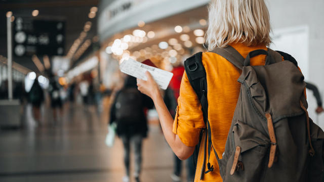 A woman at the airport holding a passport with a boarding pass 