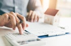 Home agents are using a calculator to calculate the loan period each month for the customer. 