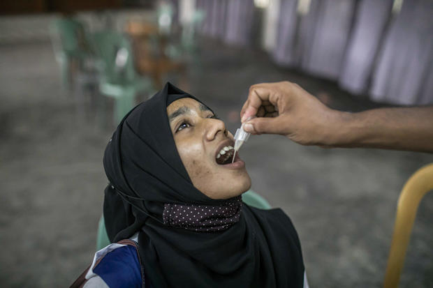 A student receives an oral cholera vaccine from a health 
