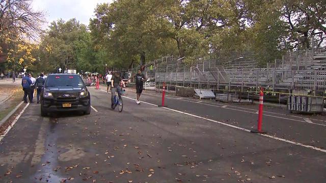 Cyclists and joggers travel past a police vehicle in Central Park. 
