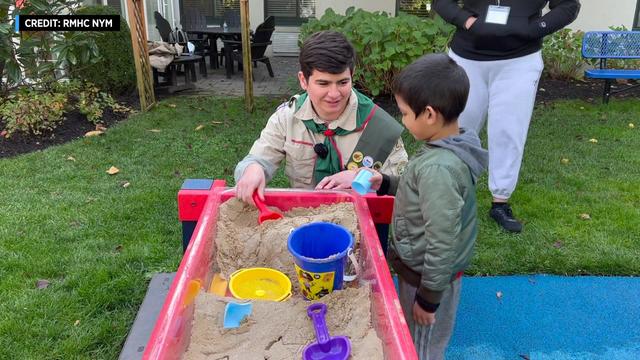 Eagle Scout candidate Max Conville plays in a sandbox with a child. 