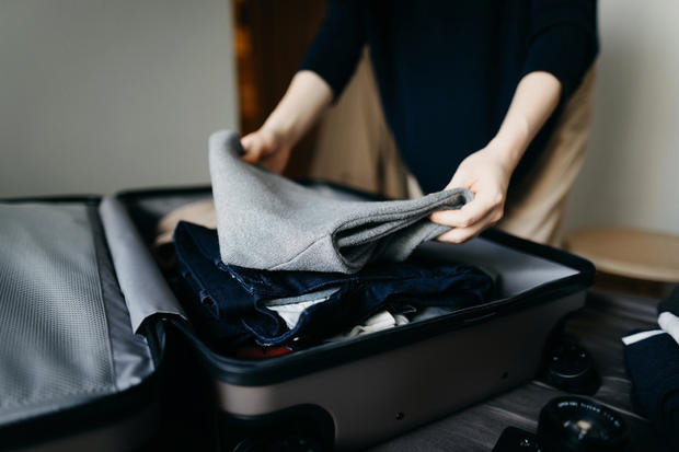 Woman packing a suitcase on bed for a trip at home 