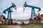 Oil pumps, nodding donkey or pump jack and rig against blue cloudy sky. Engineer in protective uniform working in between 