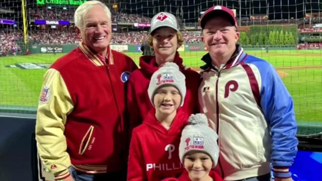 Smiling men of various ages wearing Phillies gear at ballpark 