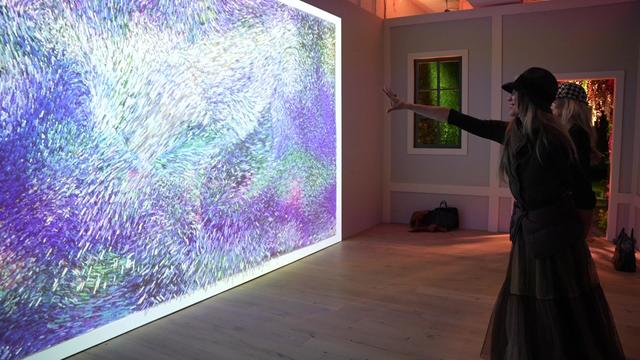 Two women stand in front of a screen with an interactive piece of artwork by Claude Monet. 