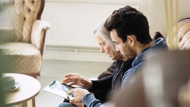 Caretaker and senior woman using digital tablet at nursing home 