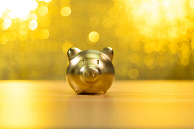 Piggy bank on shiny golden background 
