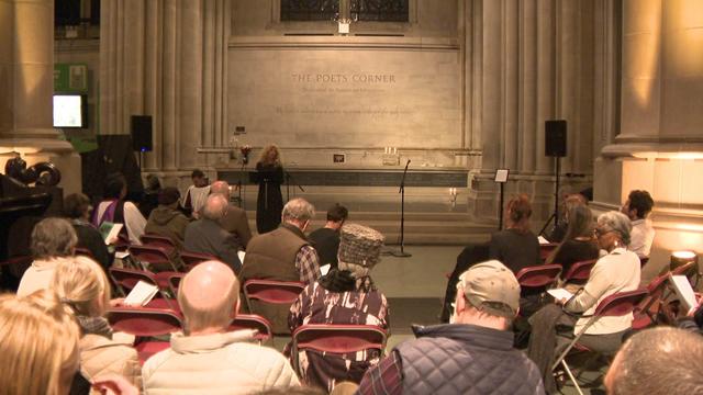 Audience members sit in chairs in front of the American Poets' Corner inside the Cathedral of St. John the Divine. 