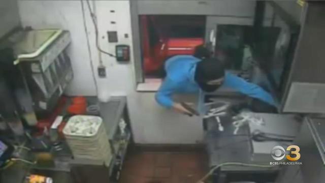 masked person reaching through open drive-thru window in fast food restaurant McDonald's. 