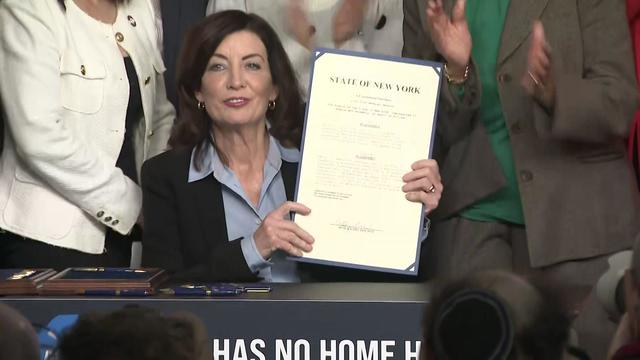 Gov. Kathy Hochul holds up an anti-hate crime bill after signing it. 