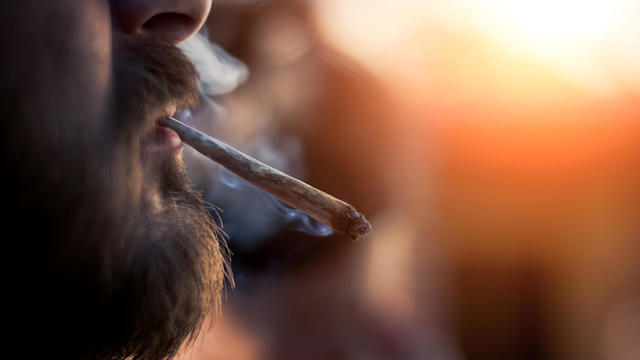 Man smoking marijuana cigarette outside on sunset 