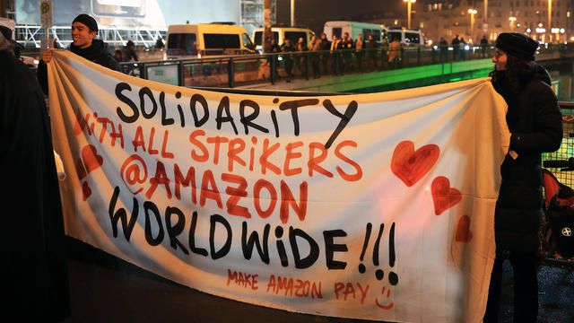 Protesters hold banner reading "Solidarity with all strikers @ Amazon worldwide" 