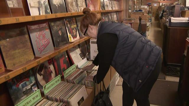 A customer looks through a box of vinyl records at a record store. 